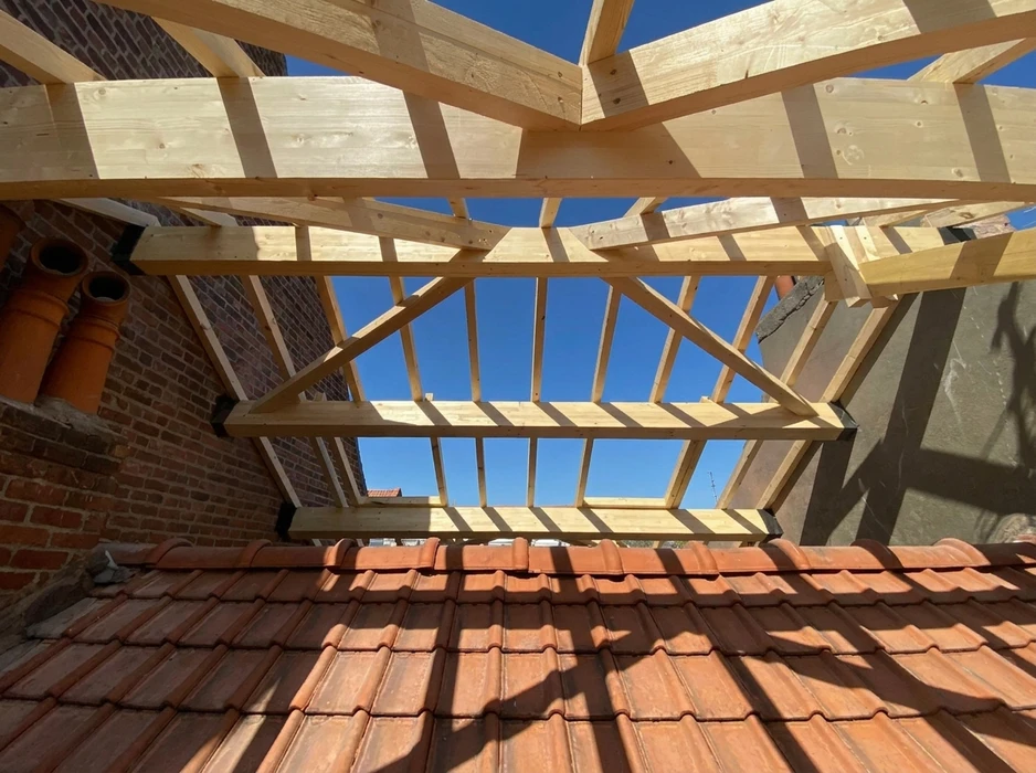 Chantier de toiture en cours, vue depuis l'intérieur vers le ciel bleu