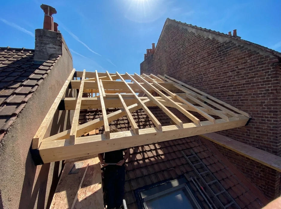 Chantier de construction extérieur sous ciel bleu avec charpente en bois en cours d'assemblage