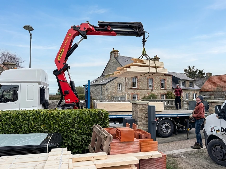 Un travailleur se tenant debout sur un échafaudage, réalise des travaux de restauration de la façade de l'ancien bâtiment