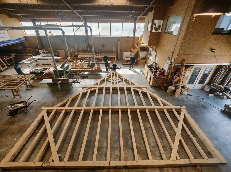 Chantier intérieur de charpente traditionnelle en bois massif résineux, posée sur un plancher en béton préfabriqué